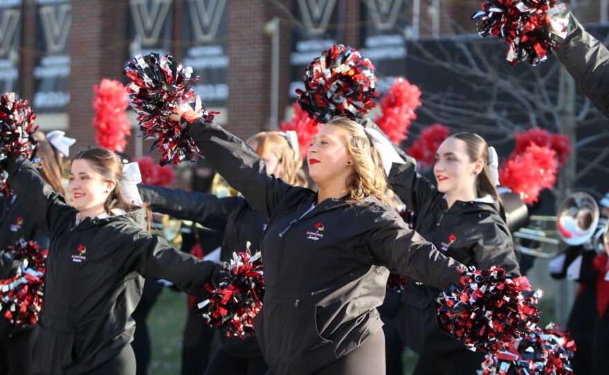 Fans and marching band members greet ISU football players and coaches