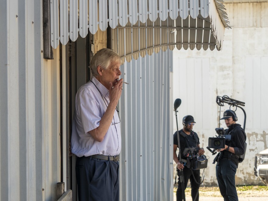 Marion County Record editor-publisher Eric Meyer takes a smoke break Oct. 15, 2025, at his newspaper office after a preliminary hearing for former Marion Police Chief Gideon Cody. A documentary crew films in the distance.