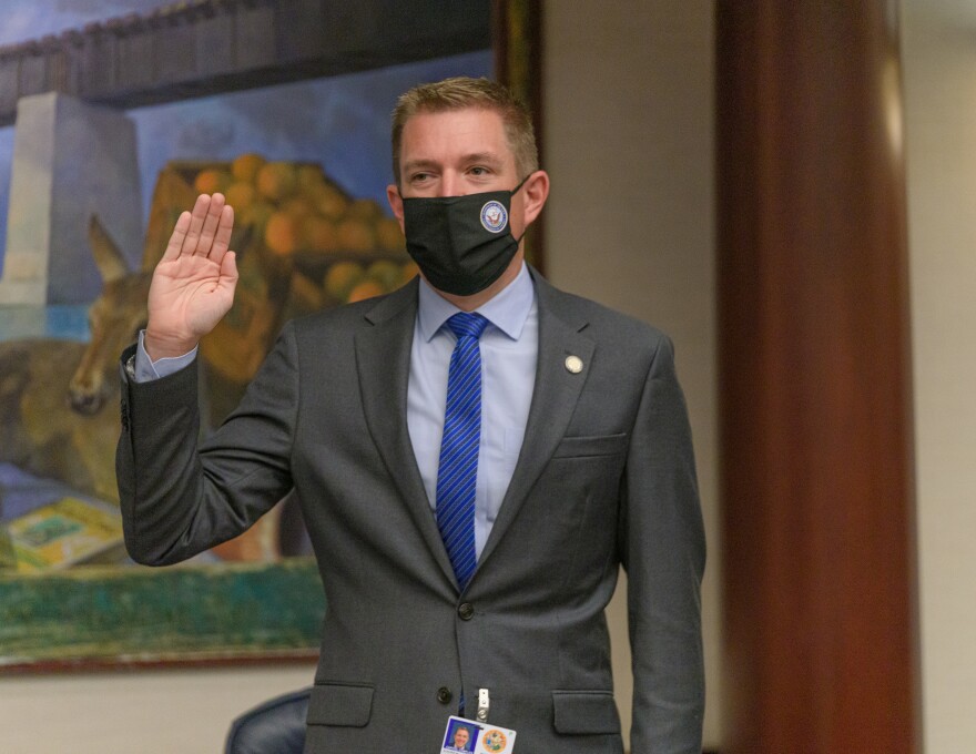 Rep. Andrew Learned, D-Pinellas, in a gray suit, raising his right hand and wearing a face mask.