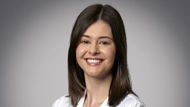 a woman in a white medical coat smiles at the camera