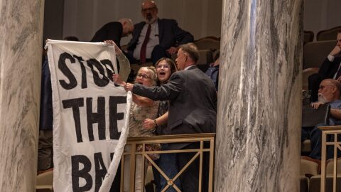 A Missouri Senate doorman shuts down protestors with a "stop the ban" banner in the Senate's upper gallery Wednesday evening