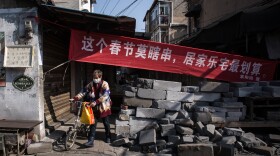Housing compounds in Wuhan are closing off many entrances to restrict movement. The banner says that even during the spring festival, staying at home is the best deal.