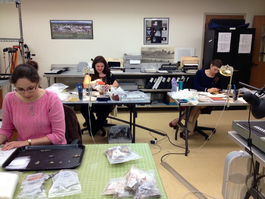 Heather Cline (middle) and Amanda Brooks (right) work daily in a lab to preserve and study artifacts found in West Virginia – huge collections of artifacts excavated from sites throughout the state. Many sites, both historic and prehistoric, were excavate