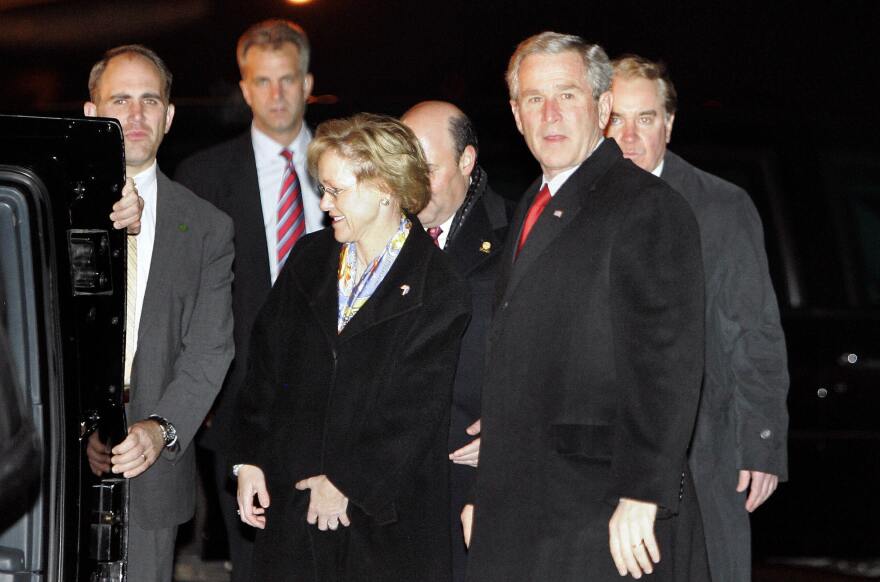 Former President George W. Bush stands beside then-U.S. Ambassador to Estonia Aldona Wos, wife of current Postmaster General Louis DeJoy, upon Bush's arrival on Nov. 27, 2006, at the airport in Tallinn, Estonia.