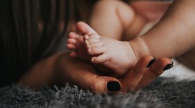 A mom cradles her baby's feet/Pixabay.