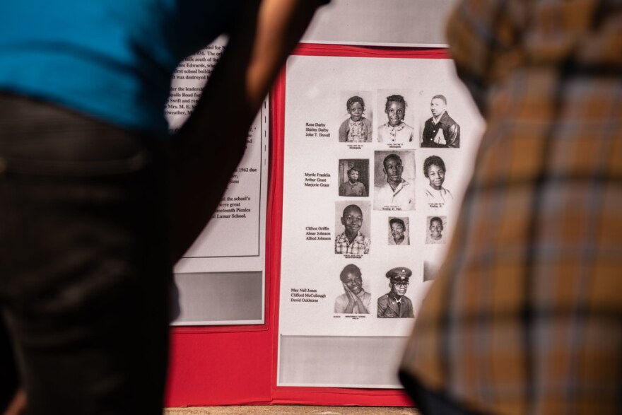 The backs of two people looking at a display of old yearbook pages