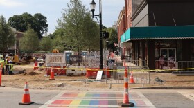 Construction underway in downtown with rainbow crosswalk.