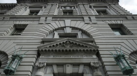 A gray building with bronze light posts flanking either side of the entrance.