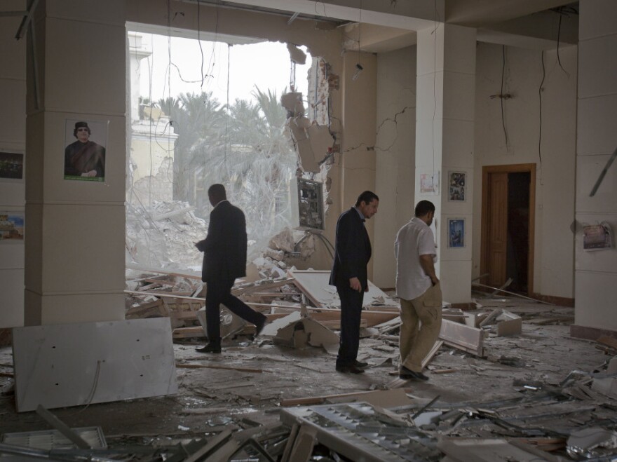 In this photo taken on a government-organized tour, officials inspect damage at the scene of an airstrike in Tripoli, Libya, on April 30.