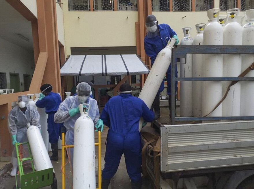 Medical workers offload cylinders of oxygen at the Donka public hospital where coronavirus patients are treated in Conakry, Guinea.