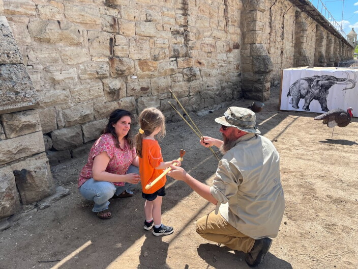 Matt Burgess shows a kid how to properly hold an atlatl at the 2023 Idaho Archaeology Fair.