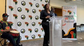 Nikia Washington, coordinator of the Rochester Juneteenth Festival, delivers closing remarks during a ceremony announcing this year's event. Behind her to the right is Simeon Banister, president and CEO of the Rochester Area Community Foundation and leader of The Greater Rochester Martin Luther King Jr. Commission, and drummer Shenuti Nehast Kawaida.