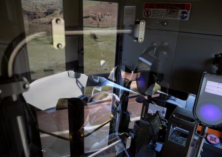 The reflection of a bus drivers in a window.