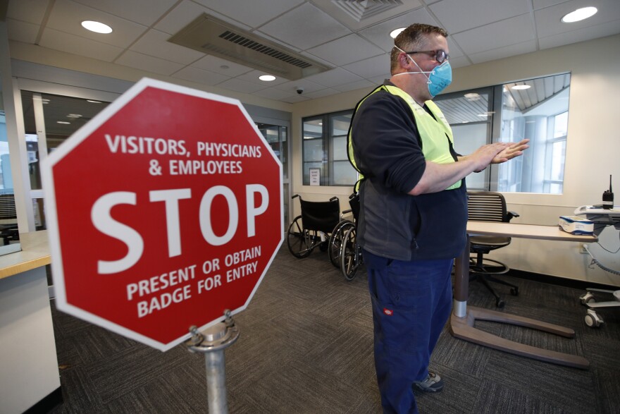 Bradley Mattes, associate nurse leader at Central Maine Medical Center, questions patients at the emergency entrance to the hospital, Friday, March 13, 2020, in Lewiston, Maine. "I refer to myself as the Walmart greeter of nurses," said Mattes, who questions patients to determine if their symptoms indicate the need for testing for the coronavirus or other medical attention.