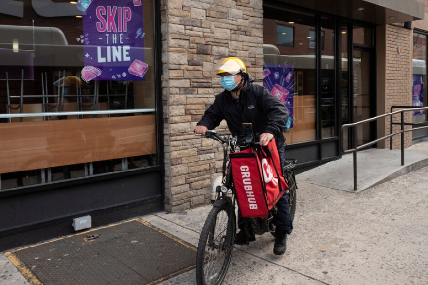 In this April 21, 2021, file photo, a delivery man bikes with a food bag from Grubhub in New York. The three biggest food delivery companies, DoorDash, Grubhub and Uber Eats, sued the City of New York in 2021 over its law to permanently limit the amount they can charge restaurants that use their services.