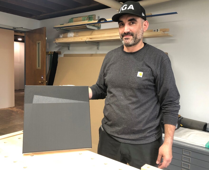 Jorge García Almodóvar holds up a black painting in his studio at Agnes Arts. He also runs an art handling company called JGA Fine Art Services.