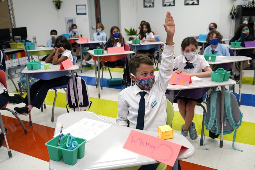 Student Winston Wallace, 9, raises his hand in class at iPrep Academy on the first day of school, Aug. 23, 2021, in Miami. 