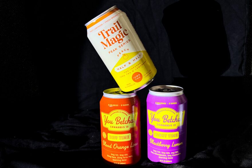Three cans of THC-infused drinks are stacked on one another in front of a black background.