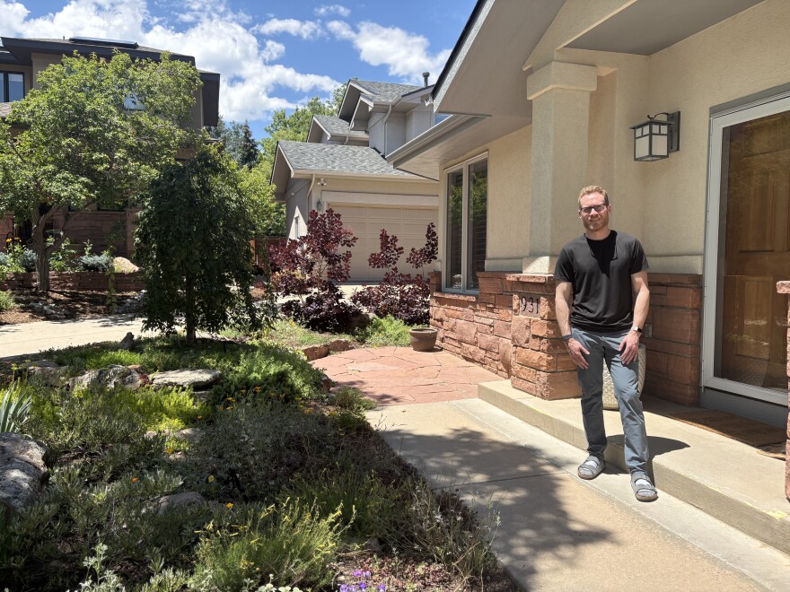 A man stands in front of a house. 