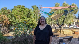 A woman smiling next to a garden.