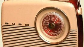 A vintage, cream-colored Bush TR82 portable transistor radio with a round tuning dial, horizontal speaker grilles, and a white carrying handle.