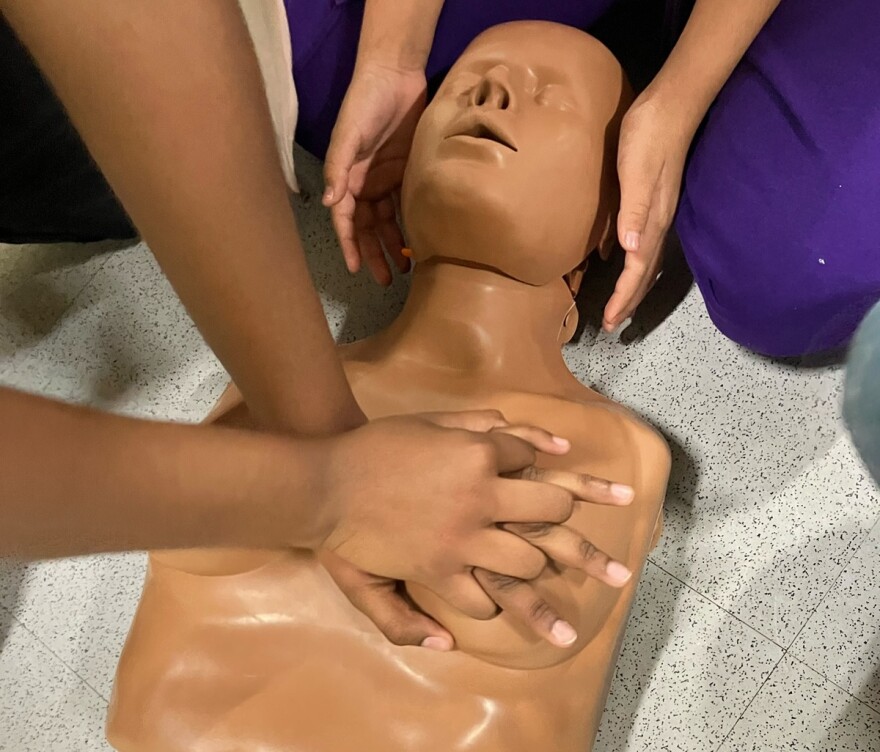 Interlocked hands placed on the left breast of a manikin as a demonstration of how to perform CPR