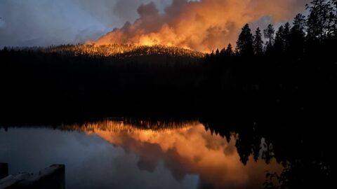 A large fire burns over a mountain during the night