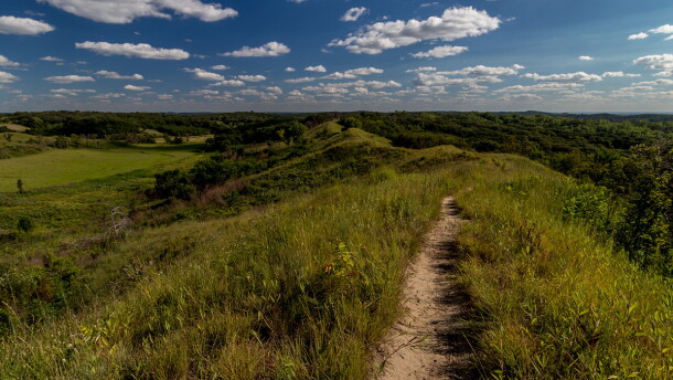 The Loess Hills are shown with green grass and a blue sky.