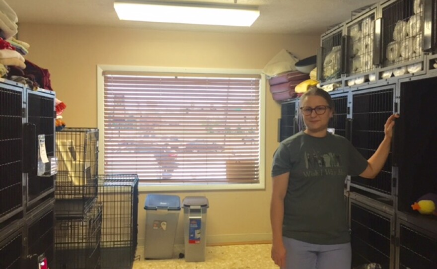 Woman posed in room with animal cages stacked on both sides.