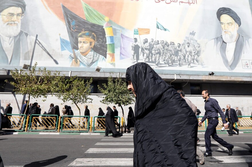 An Iranian woman walks past pictures of Iranian supreme leader Ayatollah Ali Khamenei and of late Iranian supreme leader Ayatollah Ruhollah Khomeini, following the weekly Friday prayer in Tehran on Oct. 13, 2017. (STR/AFP/Getty Images)