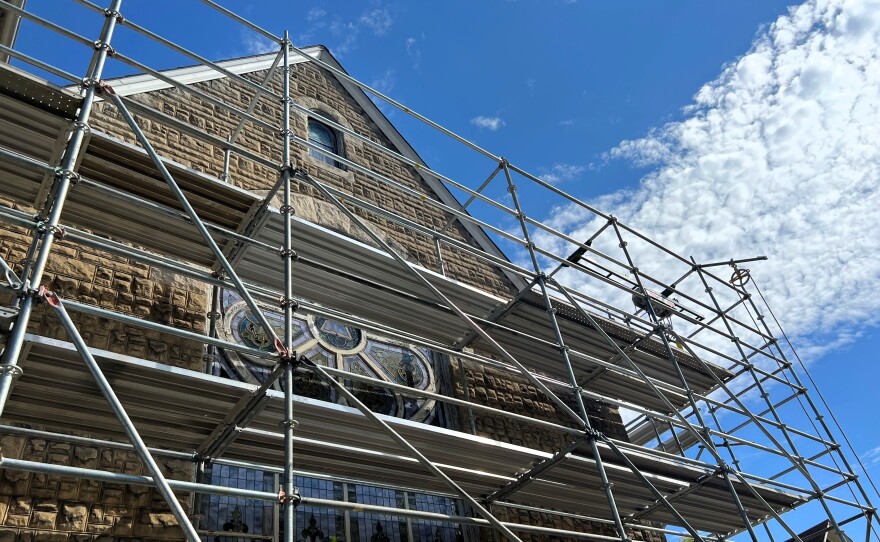 The outside of a historic building is covered in scaffolding.