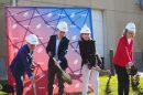 Four people dig into a pile of dirt for a groundbreaking ceremony.