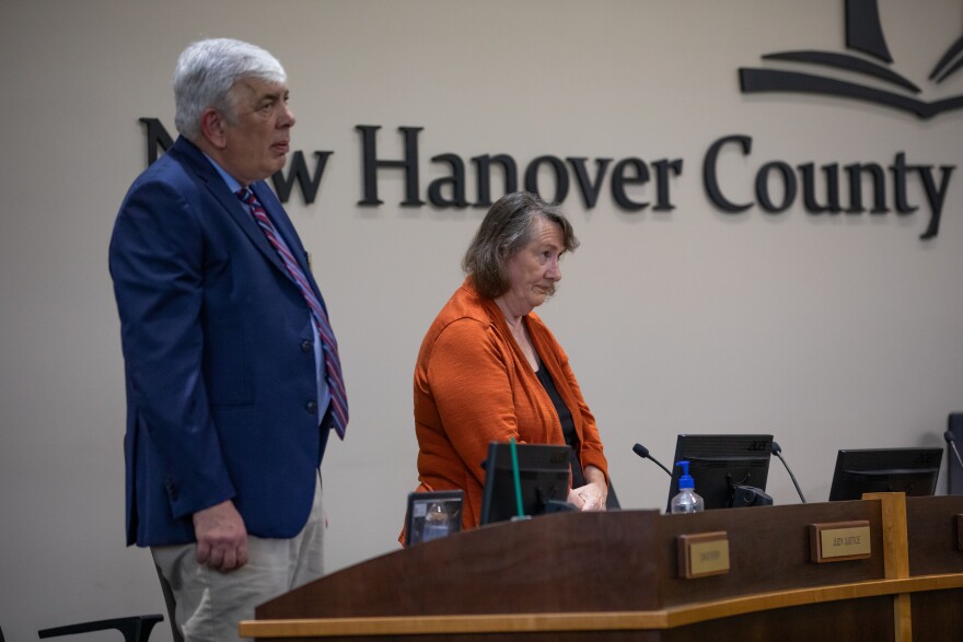 Board members David Perry, left, and Judy Justice, right, listen to God Bless America before the start of the New Hanover County Schools Board of Education meeting in Wilmington on July 8, 2025. Many teachers and community members attended to show their support for the Mary W. Howe Pre-K Center which was under consideration for closure.