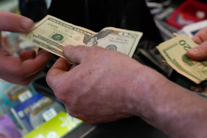 A customer uses cash at a gas station on Monday, March 16, 2026, in Portland, Ore. (AP Photo/Jenny Kane)