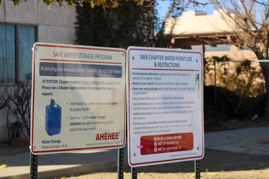 Signs describe a pump providing safe water near town administration buildings in To'hajiilee. Although a new pipeline will soon deliver clean water to the community, asbestos pipes near homes will need costly replacements.