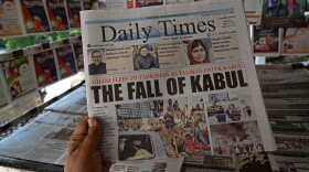 A man holds a newspaper displaying front page news about Afghanistan, at a stall in Islamabad on August 16. (Aamir Qureshi/AFP/Getty Images)