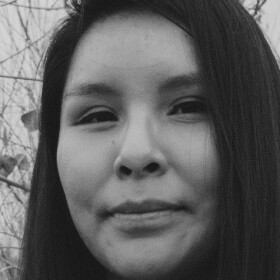 Close-up of a woman smiling at the camera in front of a dry thicket
