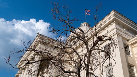Tree branches are seen in the foreground with the Alabama Capitol building behind.