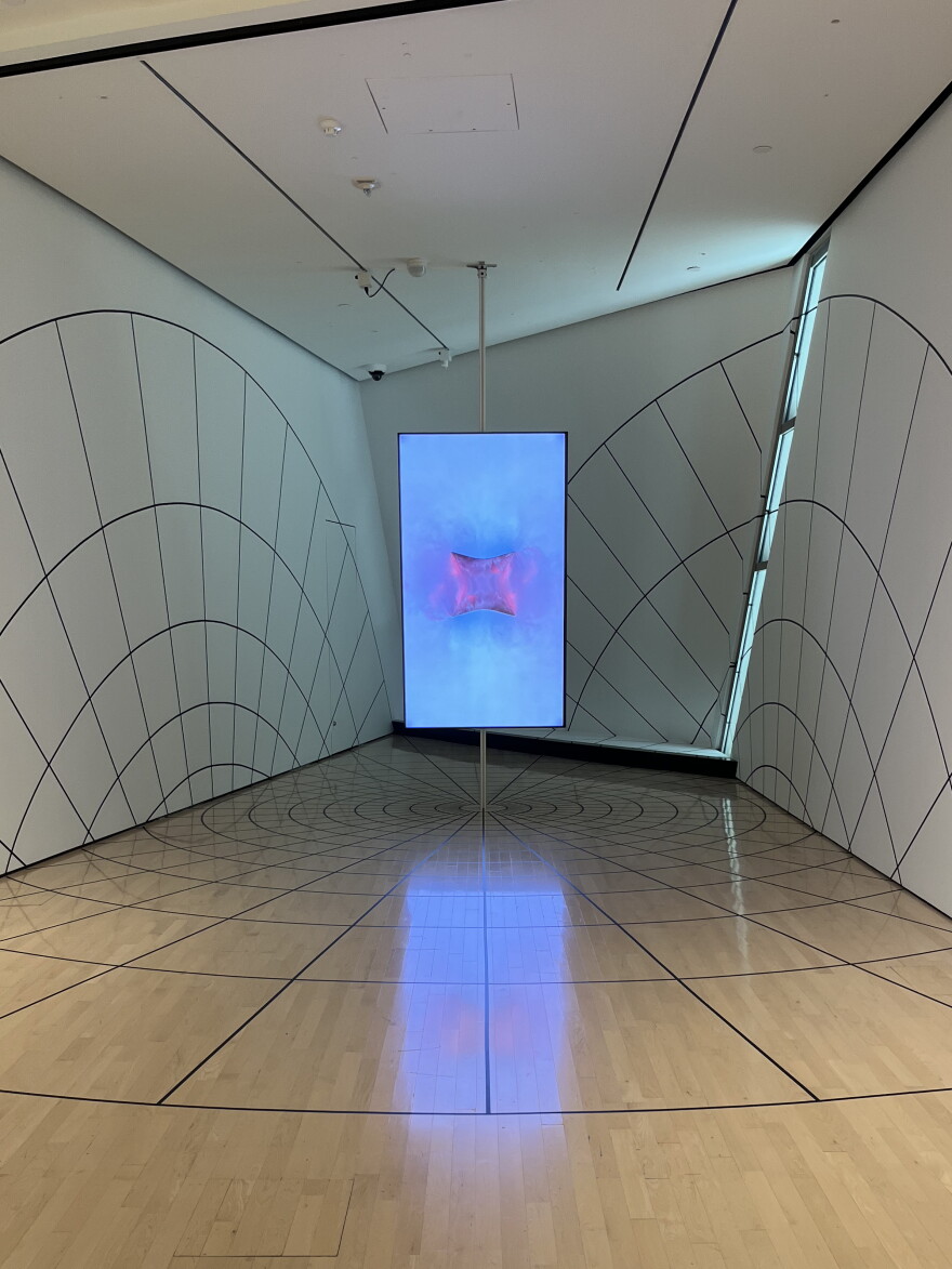Evan Roth's Skyscape at Broad Art Museum with a large screen in the back of the room with large circular geometric designs laid on the walls and floors.