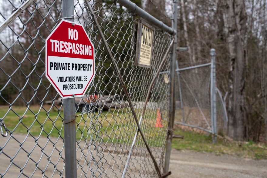 A picture of a red and white sign in front of a chained link fence 