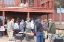 Dozens of people wait outside the Chapel In The Pines waiting to be let into the food pantry in the basement of the church. As they wait, they talk with each other and catch up.