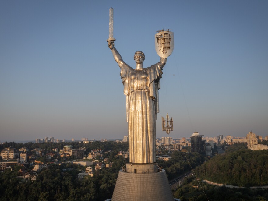 Workers install the Ukrainian coat of arms on the shield in the hand of the country's tallest stature, the Motherland Monument, after the Soviet coat of arms was removed, in Kyiv, Ukraine, Sunday, Aug. 6, 2023. Ukraine is accelerating efforts to erase the vestiges of centuries of Soviet and Russian influence from the public space.