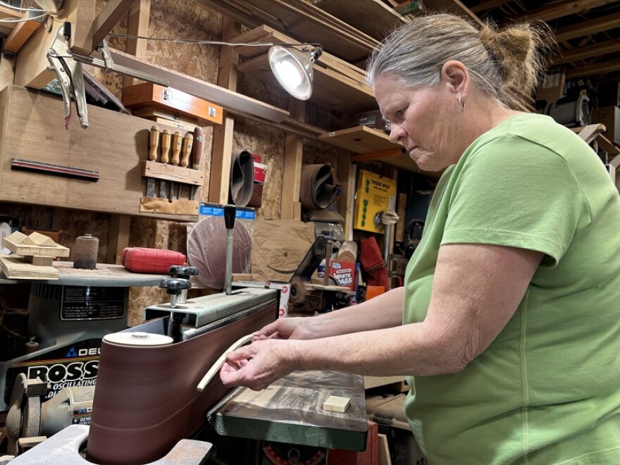Aleta Stone demonstrates how she prepares a piece of wood in her workshop for her collages.