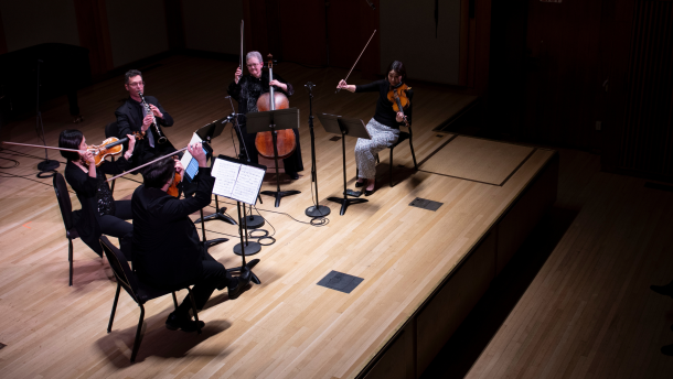 In the darkness of Pickman Hall, one spot light illuminates four players: two violins, one viola, one cello, and one clarinet shimmer in the light.