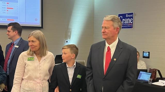 Idaho Governor Brad Little standing with two other people.