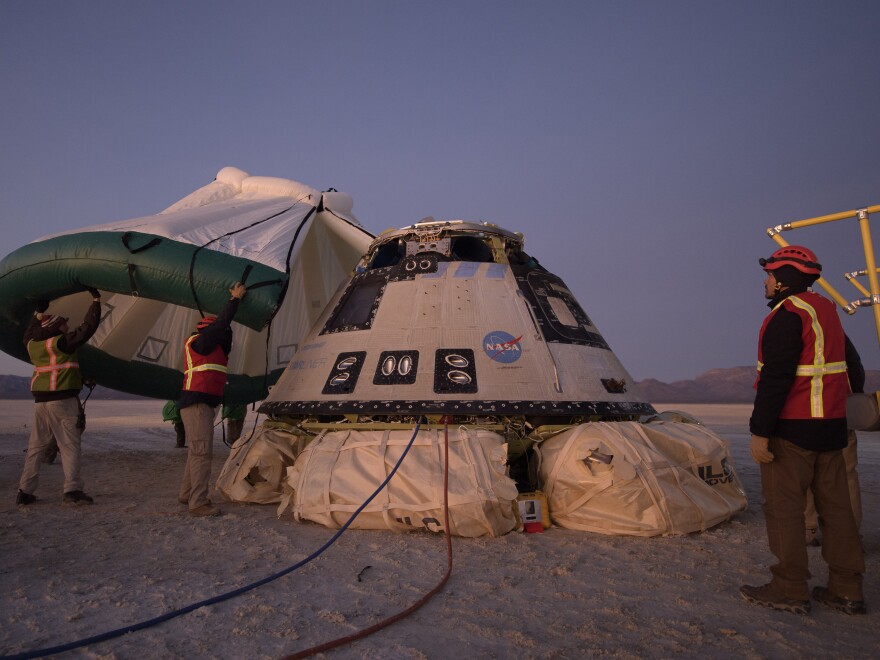 Boeing, NASA, and U.S. Army personnel work around the Boeing Starliner spacecraft shortly after it landed in White Sands, N.M., Sunday.