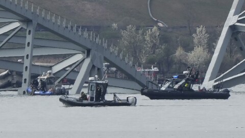 Boats move near a container ship as it rests against wreckage of the Francis Scott Key Bridge on Tuesday, March 26, 2024, as seen from Dundalk, Md. The ship rammed into the major bridge in Baltimore early Tuesday, causing it to collapse in a matter of seconds and creating a terrifying scene as several vehicles plunged into the chilly river below. (AP Photo/Matt Rourke)