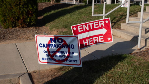 Two signs outside of a polling location which say "No campaigning" and "Vote here"