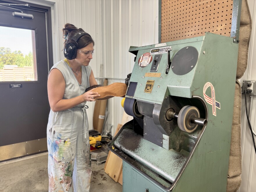 Marcie She holds up the sole of a cowboy boot to a cutting machine.