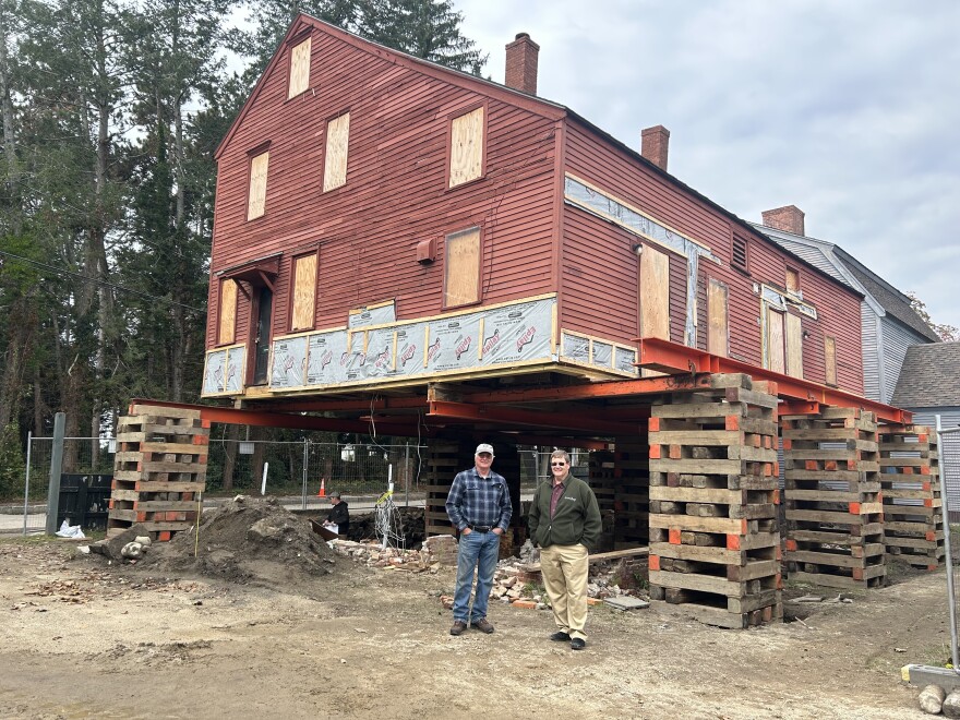 Rodney Rowland and Arron Sturgis stand in front of the Penhallow House, on the day it was raised into the air. The house will come back down after a new climate-resilient foundation is installed.